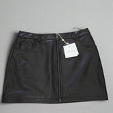 Black leather skirt with a tag on a tiled floor